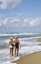 Two elderly women walking and talking on the beach.