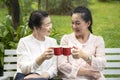 Two elderly women who were friends were bumping into a glass to celebrate friendship in the backyard