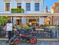 Two electric bicycles are parked near the open veranda of a summer cafe in the Riga Old Town