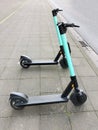 Two electric kick scooters or e-scooter parked on sidewalk