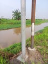 Two electric poles by the brown river water Royalty Free Stock Photo