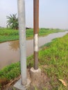 Two electric poles by the brown river water Royalty Free Stock Photo