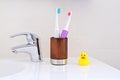 Two electric toothbrushes in wooden glass on sink in the bathroom