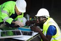 Two electrical engineers working with electronic circuit board and solar cells, mechanicals senior white and African American men