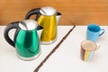 Electrical kettles with mugs and handful coffee beans on the wood and marble background