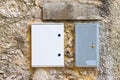 Two electrical plastic junction box against a stone and brick wa