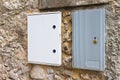 Two electrical plastic junction box against a stone and brick wa