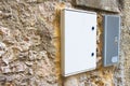 Two electrical plastic junction box against a stone and brick wall