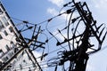 Two electrical poles with complex wiring against a blue cloudy sky