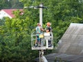 Two electricians repair high voltage power lines. Technology of work on electric poles in the city. Safety precautions for work at