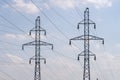 Two electricity poles and power lines against morning blue sky with white soft clouds. Energy supply Royalty Free Stock Photo