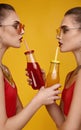 Two elegant glamor hipster twin girls in fashion red top with cocktail drink Royalty Free Stock Photo