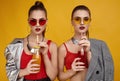 Two elegant glamor hipster twin girls in fashion red top with cocktail drink Royalty Free Stock Photo