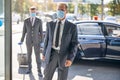 Two elegant men in masks entering airport