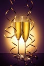 Two elegant perfect glasses filled with fizzy drink or sparkling champagne with golden streamers of serpentine on golden backgroun Royalty Free Stock Photo