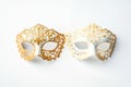 Two elegant, side-by-side masquerade masks feature delicate gold filigree patterns