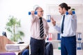 Two employees doing physical exercises at workplace