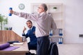 Two employees doing physical exercises at workplace