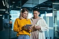 Two employees are having fun. during the break an Asian man and a blonde woman, colleagues work together in a modern office, look Royalty Free Stock Photo