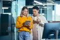 Employees are having fun. during the break an Asian man and a blonde woman, colleagues work together in a modern office, look Royalty Free Stock Photo