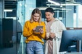 Employees are having fun. during the break an Asian man and a blonde woman, colleagues work together in a modern office, look Royalty Free Stock Photo