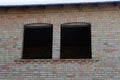 Two empty black windows on a brown brick wall of an unfinished house Royalty Free Stock Photo