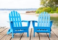 Blue adirondak chairs on wooden pier by lake in summer Royalty Free Stock Photo