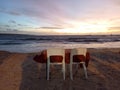 Two empty chairs on the beach with red romantic table and colorful sunset sky background. Royalty Free Stock Photo