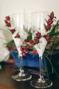 Two empty champagne glasses decorated with white lace and red roses flowers on hotel room table, morning wedding preparation Royalty Free Stock Photo