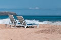 Two empty deck chairs on a deserted sandy beach on the ocean. Royalty Free Stock Photo