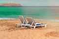 Two empty deck chairs on a deserted sandy beach on the ocean. Royalty Free Stock Photo