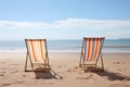 two empty deckchairs facing the ocean on a sandy beach