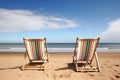 two empty deckchairs facing the ocean on a sandy beach