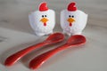 Two empty eggcups looking like a chicken with red spoons