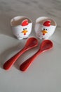 Two empty eggcups looking like a chicken with red spoons Royalty Free Stock Photo