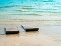 Two empty floating sunbed seats on the clean blue water sea wave and sandy beach background with nobody. Royalty Free Stock Photo