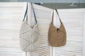 Two empty knitted bags hanging on wooden door. Ad and buy concept