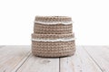 Two empty knitted beige baskets stand in the form of a tower on a table on a white background.