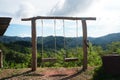 Two empty lonely hanging wooden swings on top of a hill with a beautiful view of the mountains. Royalty Free Stock Photo