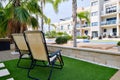 Two empty lounge chairs on artificial lawn grass inside of personal area backyard residential summer villa Royalty Free Stock Photo