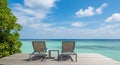 Two Empty Lounge Chairs on a Wooden Deck Facing a Tropical Ocean and Blue Sky vacation beach Royalty Free Stock Photo