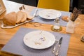 Two empty plates standing on linen plate with polka dots, and sliced fresh bread on wooden kitchen table.ts