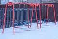 Two empty red metal swings on a playground in white snow Royalty Free Stock Photo