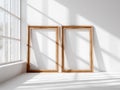 Two Empty Rustic Wooden Picture Frames on White Wall Next to Window with Sunlight Shadows Royalty Free Stock Photo
