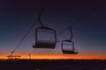 two empty seats that are going up a hill at sunset