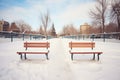 two empty snow-covered benches with footprints leading away Royalty Free Stock Photo