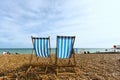 Two empty striped folding beach chairs on seacoast in Brighton, unknown people Royalty Free Stock Photo