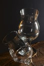 Two empty tulip beer glasses on dark wooden table over black background.