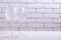 Two empty wine glasses on a table against a brick wall