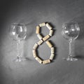 Two empty wine glasses with wine corks over grey background. Number eight 8 made from corks, International Womans Day